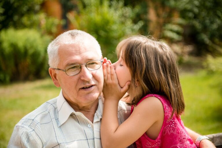 child whispering to grandfather